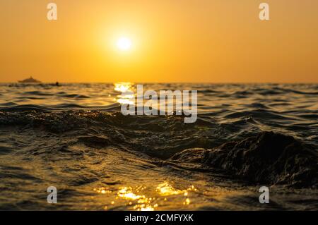 vague de mer gros plan au coucher du soleil avec reflet du soleil rouge et orange sur l'eau. nature résumé bl Banque D'Images