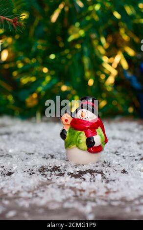 Bonhomme de neige en céramique parmi les lumières de Noël sur fond flou Banque D'Images