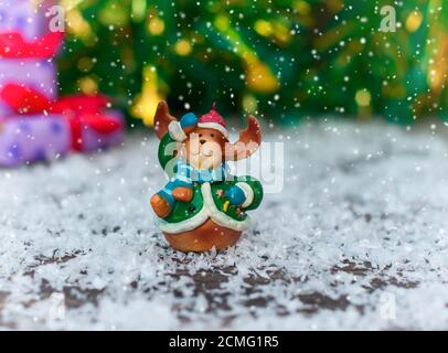 Jouets de Noël en céramique elk en vêtements de fête, debout dans la neige, la neige sur le haut de jette Banque D'Images