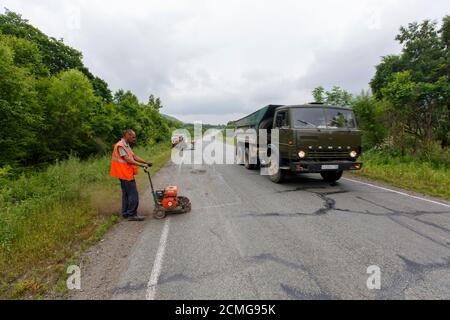 Réparation d'une mauvaise route. Les travailleurs pavent une mauvaise route dans une forêt en Russie. Banque D'Images