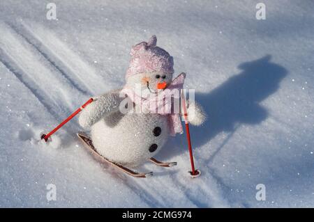 Un bonhomme de neige en tissu sur des skis en bas d'une pente avec de la neige Banque D'Images