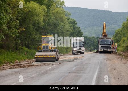 Réparation d'une mauvaise route. Les travailleurs pavent une mauvaise route dans une forêt en Russie. Banque D'Images