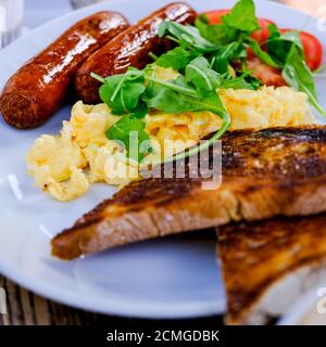 Petit déjeuner anglais sain œufs brouillés avec saucisses de porc et toasts Banque D'Images