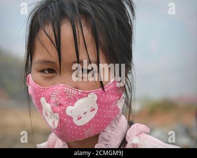 La jeune fille de la minorité ethnique vietnamienne Hmong couvre son nez et sa bouche avec un masque protecteur lavable en rose. Banque D'Images