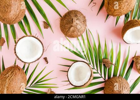 Motif, texture avec noix de coco et feuilles de palmier tropicales sur fond rose. Arrière-plan tropical abstrait. Flat lay, vue de dessus. Banque D'Images