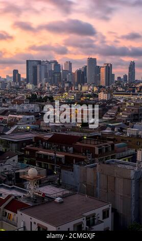 Vue sur la banlieue dense de Nakano et sur la Horizon de Shinjuku pendant un lever de soleil d'été sous un ciel partiellement nuageux ciel Banque D'Images