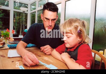 Père aidant la fille avec des compétences d'alphabétisation Banque D'Images