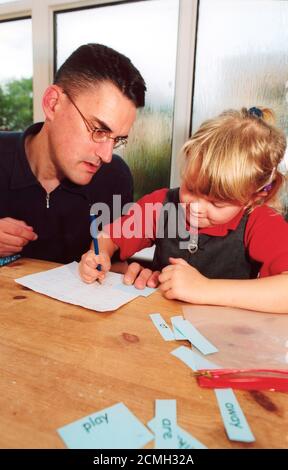 Père aidant la fille avec des compétences d'alphabétisation Banque D'Images