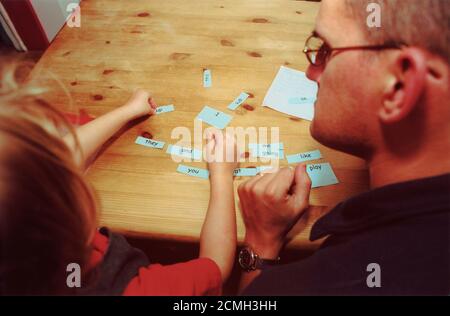 Père aidant la fille avec des compétences d'alphabétisation Banque D'Images