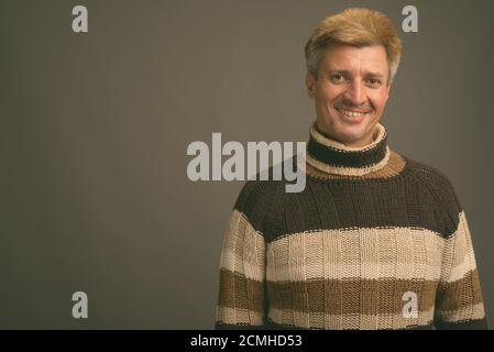 Portrait d'un homme heureux aux cheveux blonds portant un pull à col roulé Banque D'Images