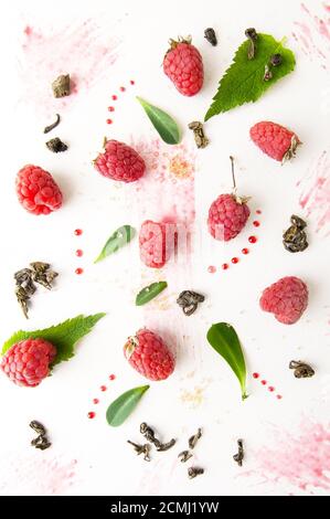 Framboises mûres, feuilles de menthe, confiture et thé vert sur fond blanc. Banque D'Images