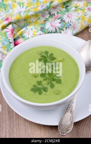 Une assiette de soupe purée de petits pois au persil sur une table Banque D'Images