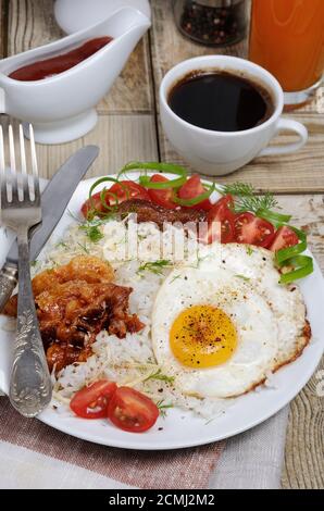 Le petit déjeuner - riz bouilli avec des œufs brouillés, bacon, les tranches de tomate et les verts Banque D'Images