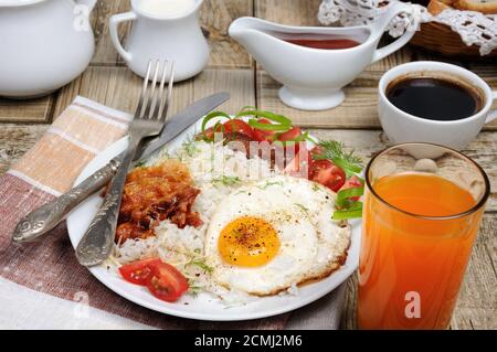 Le petit déjeuner - riz bouilli avec des œufs brouillés, bacon, les tranches de tomate et les verts Banque D'Images