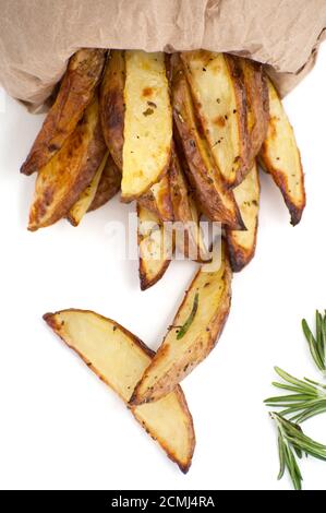 Tranches de pommes de terre rustiques cuites au four au romarin sur fond blanc. Banque D'Images