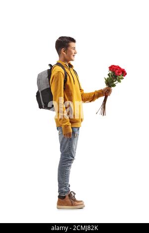 Prise de vue en longueur d'un étudiant adolescent de sexe masculin tenant un bouquet de roses rouges isolées sur fond blanc Banque D'Images