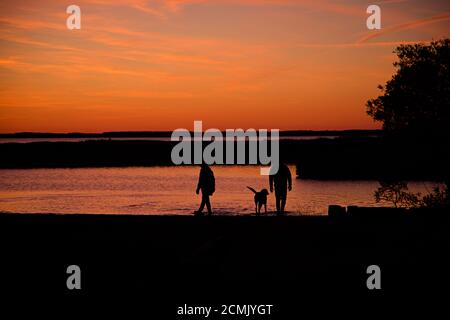Coucher de soleil sur l'île d'Assateague au-dessus des marais, baie d'eau salée avec une silhouette de couple marchant sur le bord Banque D'Images
