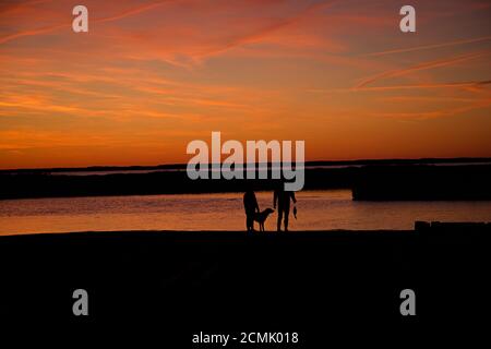 Coucher de soleil sur l'île d'Assateague au-dessus des marais, baie d'eau salée avec une silhouette de couple marchant sur le bord Banque D'Images