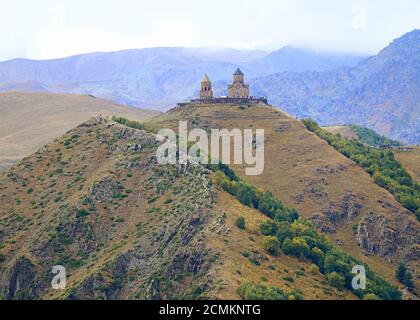 Vue incroyable sur l'église de la Trinité de Gergeti ou Tsminda Sameba sur la colline avec grand groupe de Vositors, ville de Stepantsminda, Géorgie Banque D'Images