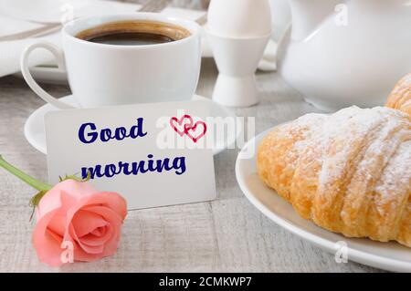 Petit-déjeuner composé de croissants au chocolat et d'une tasse de café frais le matin Et une carte avec un bon souhait Banque D'Images