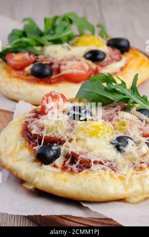 Mini pizza avec de la saucisse et l'oeuf et la roquette pour le petit déjeuner Banque D'Images