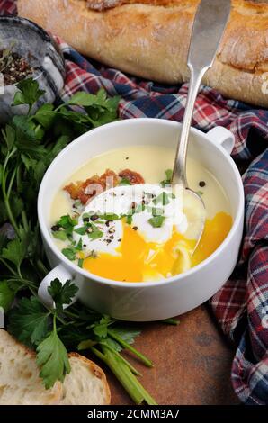 Pomme de terre à l'ail soupe de crème aux lardons et œufs pochés, herbes, épices Banque D'Images