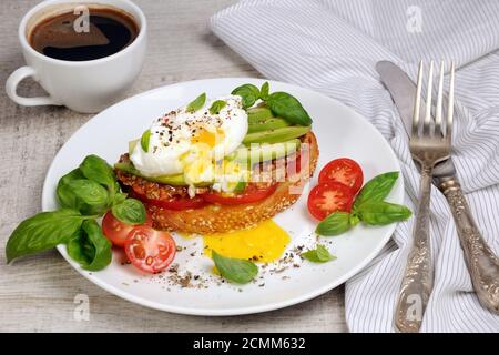 Oeuf poché sur une tranche de baguette grillée avec tomate, jambon épicé et avocat, épices saupoudrées et Banque D'Images