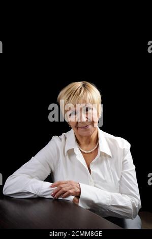 Portrait d'une femme âgée (70 +) dans un costume d'affaires contre un fond sombre Banque D'Images