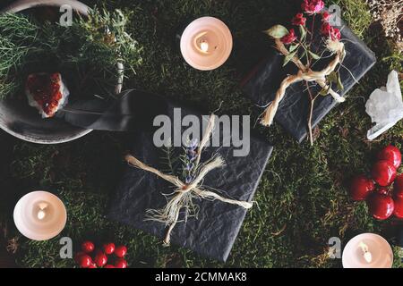 Yule (Noël) plat sur le thème de cadeaux noirs sur fond de forêt naturelle. Humeur occulte ésotérique de cadeaux enveloppés dans du papier de tissu noir Banque D'Images