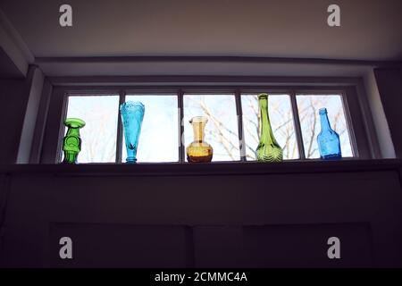 Vases en verre de couleur vintage dans une rangée sur une fenêtre seuil Banque D'Images