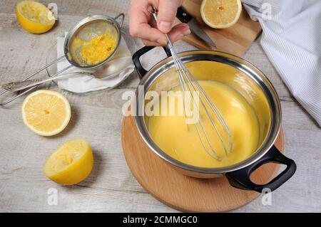 Kurdes - citron fraîchement préparés sur les jus de fruits, crème anglaise dans une casserole fouettée avec un fouet Banque D'Images