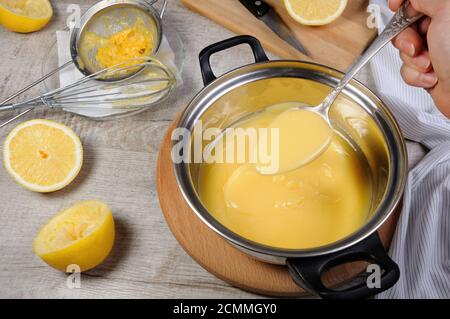 Kurde de citron fraîchement préparés - crème anglaise sur les jus de fruits dans une casserole, remuer avec une cuillère Banque D'Images