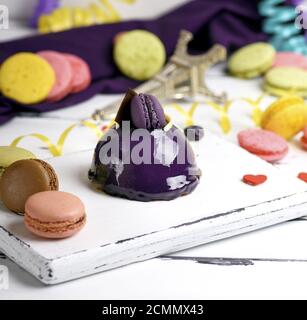 Gâteau rond lilas avec des macarons sur une planche de bois blanc Banque D'Images