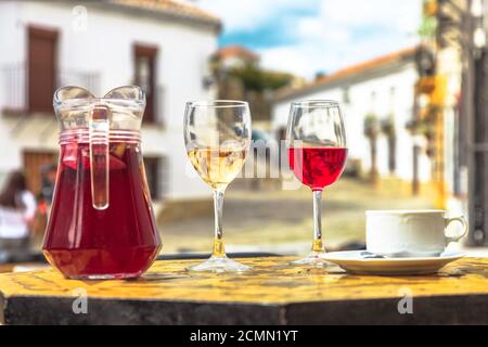 Pichet de sangria avec une tasse de café et des verres de vin rouge et blanc sur un fond flou de campagne espagnole en Espagne. Banque D'Images