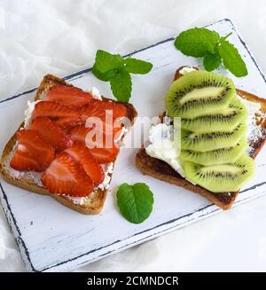 Deux toasts avec du caillé doux, tranches de fraise et kiwi Banque D'Images