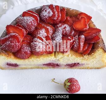 La moitié d'un gâteau au fromage aux fraises sur une plaque en céramique blanche Banque D'Images
