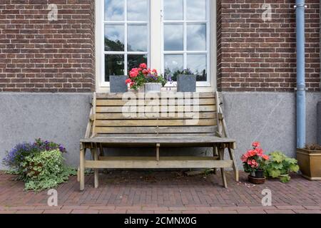 Vue avant d'un banc en bois devant un maison avec des reflets dans la fenêtre Banque D'Images