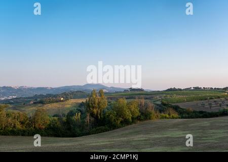 Toscane, paysage rural en Crète Senesi pays. Collines ondoyantes, ferme de campagne, cyprès des arbres, champ vert sur un coucher de soleil chaud. Sienne, Italie Banque D'Images