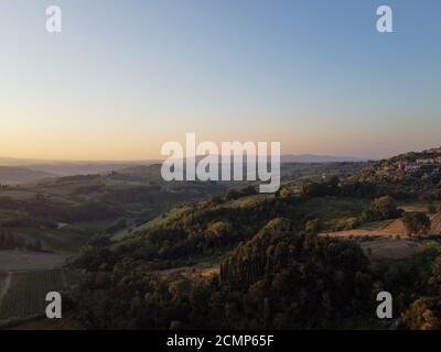 Toscane, paysage rural en Crète Senesi pays. Collines ondoyantes, ferme de campagne, cyprès des arbres, champ vert sur un coucher de soleil chaud. Sienne, Italie Banque D'Images