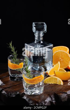 Cocktail classique de gin sec avec tonique et zeste d'orange avec une branche de romarin sur une planche de bois avec Banque D'Images