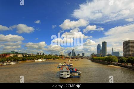 Vue panoramique sur la Tamise avec divers bâtiments emblématiques et barges contre un ciel bleu ciel nuageux Banque D'Images