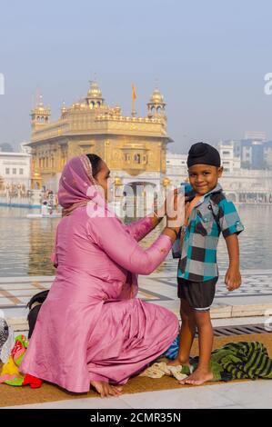 Amritsar, Inde - 21 novembre 2011 : la famille Sikh de pèlerins, mère et fils, habille un terrain de baignade dans le lac du temple d'Or. Banque D'Images