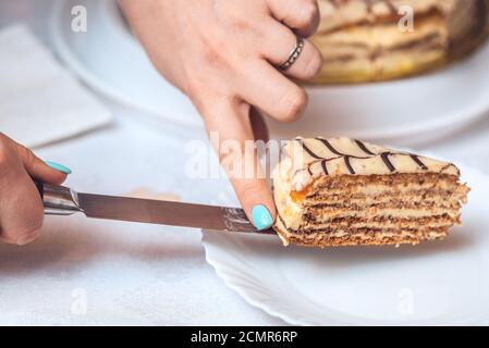 torte esterhazy entière et une tranche de gâteau sur le couteau. Les mains de la femme le tiennent. Recette authentique, dessert hongrois et autrichien, vie Banque D'Images