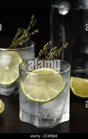 Gin Tonic avec une tranche de lime et branches de thym Banque D'Images