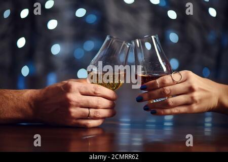 Un couple fait un toast avec deux verres de whisky sur fond de fête Banque D'Images