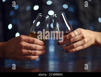 Un couple fait un toast avec deux verres de whisky sur fond de fête Banque D'Images