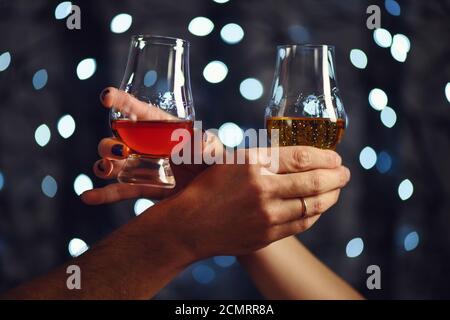 Un couple fait un toast avec deux verres de whisky sur fond de fête Banque D'Images