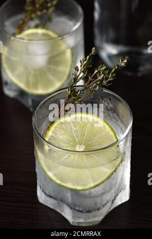 Gin Tonic avec une tranche de lime et branches de thym Banque D'Images