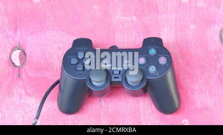 Joystick, contrôleur de jeu noir avec contrôleurs, avec plusieurs boutons, utilisé dans les jeux vidéo d'ordinateur, simulateurs et bloc-notes, dos en bois rouge Banque D'Images