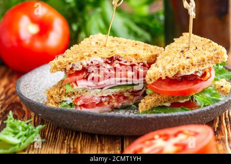 Délicieux sandwichs club avec salade verte, laitue, jambon, bacon, tomates fraîches et sauce. Concept déjeuner. Mise au point sélective Banque D'Images